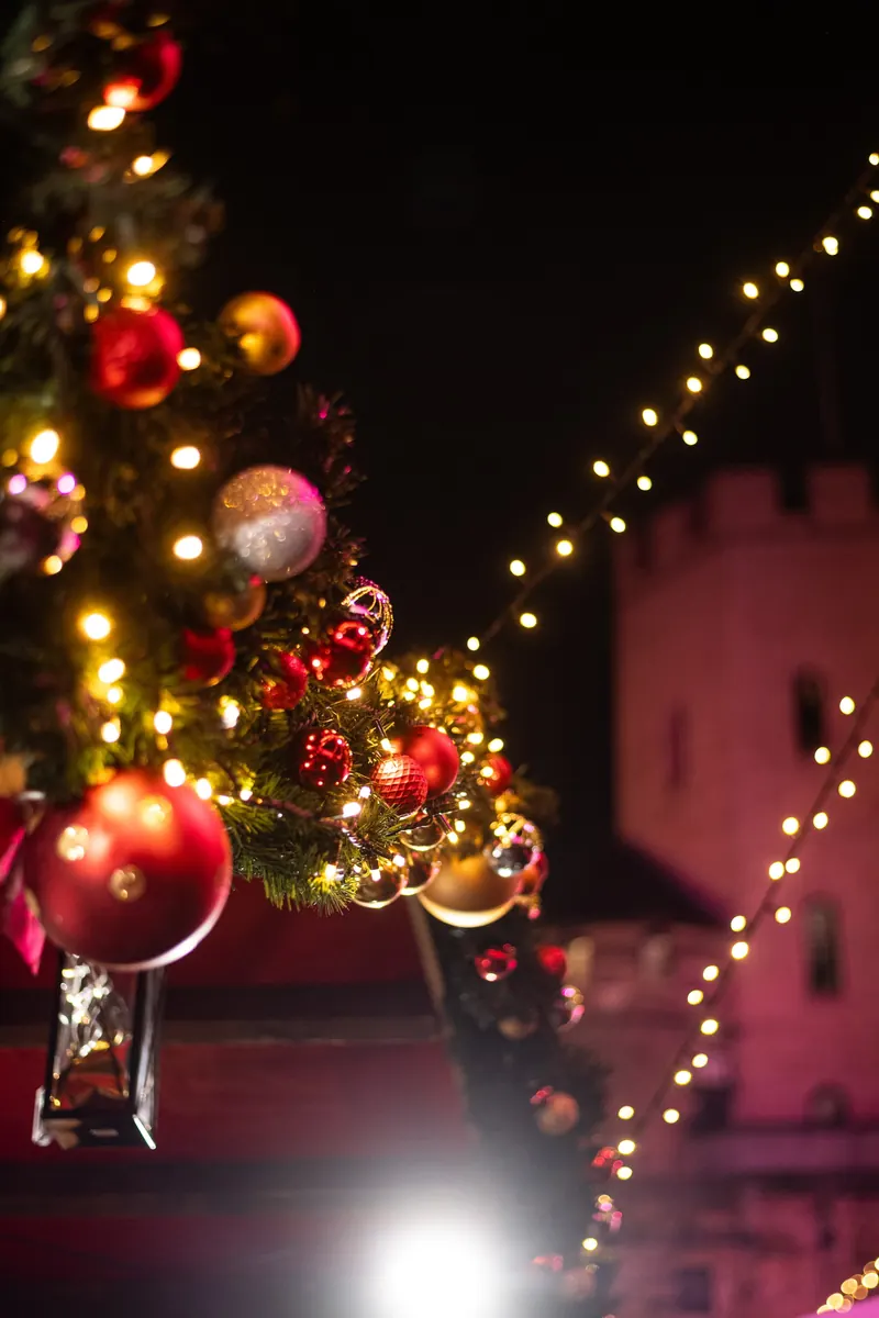 Rote und goldene Christbaumkugeln, im Hintergrund der rosa beleuchtete Turm